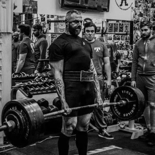 Paul Wood performing a deadlift in the gym, demonstrating proper form and strength as he lifts a heavy barbell.